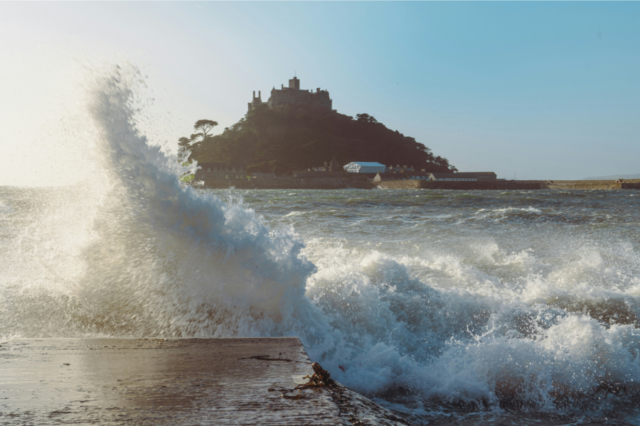 this image shows a stormy cornish scene of waves crashing in front of St Michaels mount.