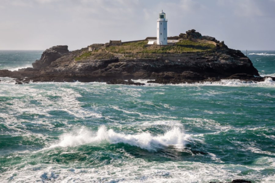 Godrevy lighthouse surrounded by a choppy, roughs sea.