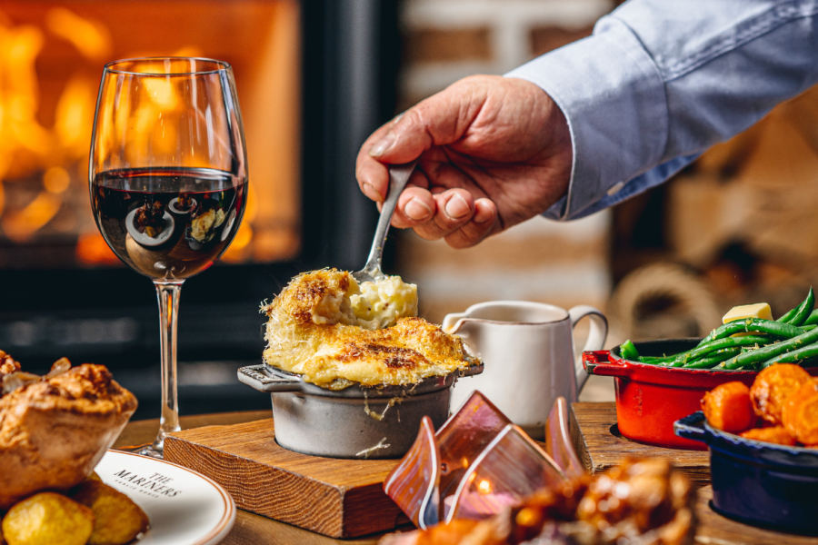 A person serving up cauliflower cheese at the mariners pub. 